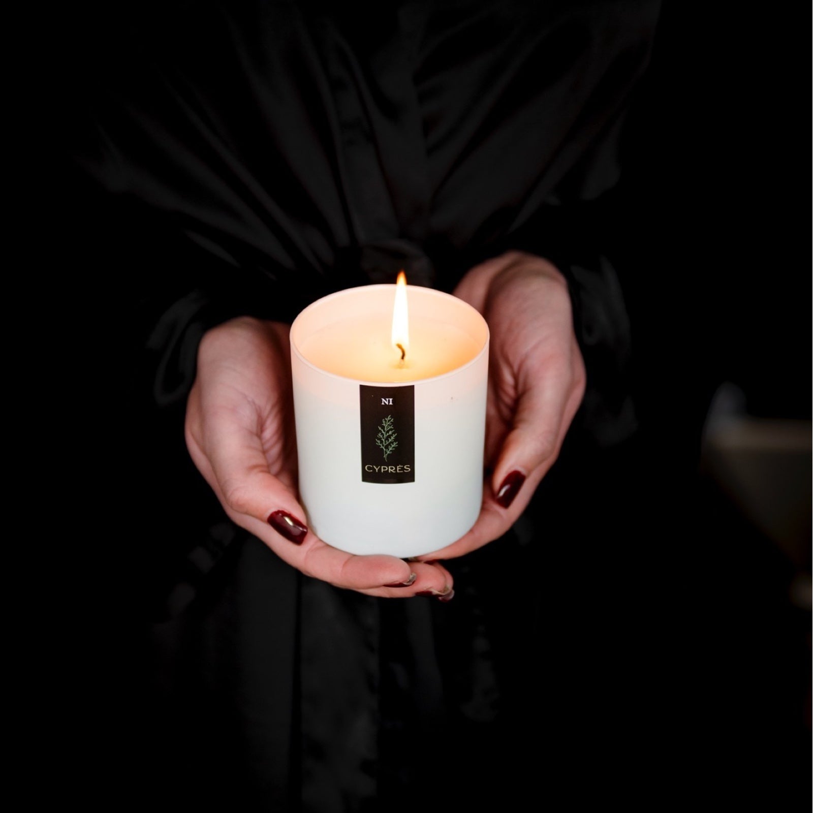 natural inspirations cyprès candle held by a model wearing a black robe