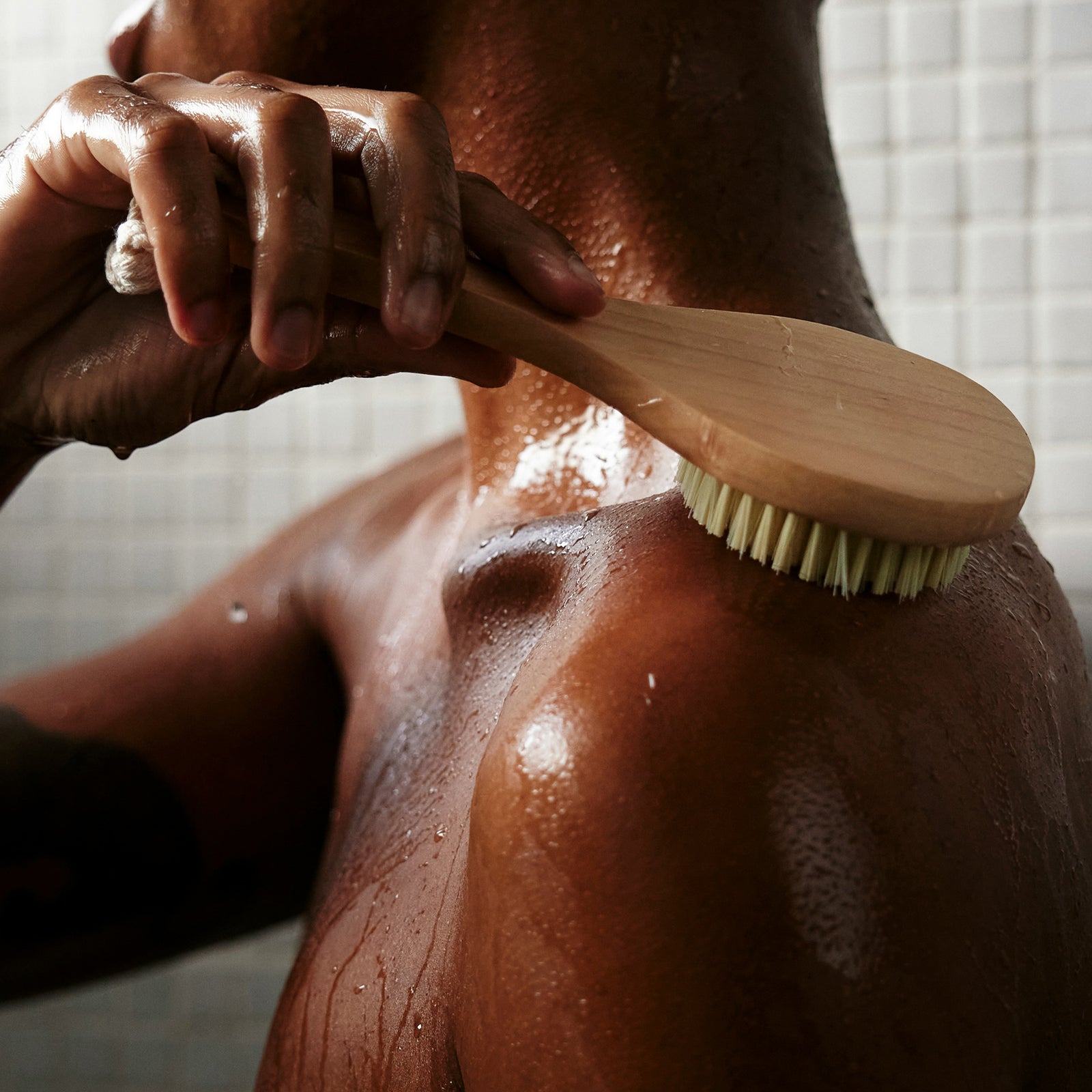 a person exfoliating in the shower with a scrub brush